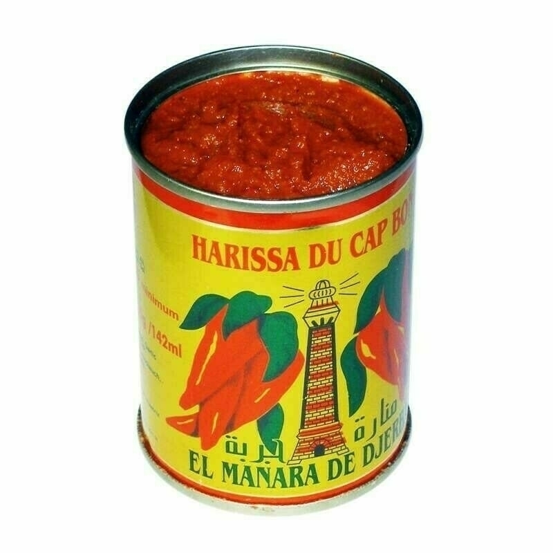 A tin of 'Harissa du Cap Bon' stands open, revealing its spicy red contents, set against a white background.
Spanish: Una lata de 'Harissa du Cap Bon' está abierta, mostrando su contenido rojo picante, sobre un fondo blanco.
Basque: 'Harissa du Cap Bon'eko lata bat irekita dago, bere eduki gorri minak erakutsiz, zuri koloreko atzealdean.