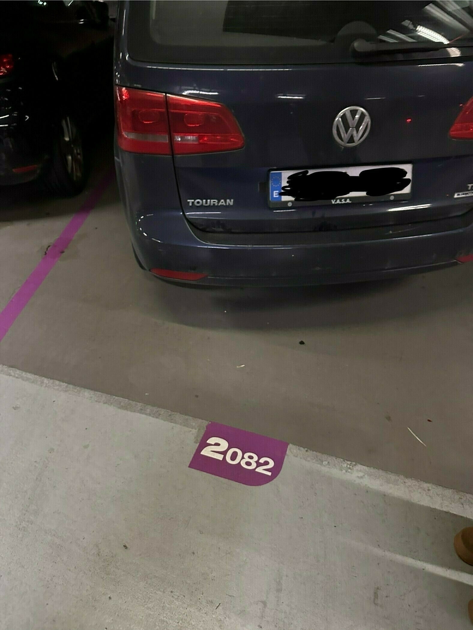 A blue car parked in a garage, with the number 2082 on the ground, indicating a parking spot.
Spanish: Un coche azul estacionado en un garaje, con el número 2082 en el suelo, indicando una plaza de aparcamiento.
Basque: Auto urdin bat aparkatuta garaje batean, 2082 zenbakia lurrean, aparkaleku bat adieraziz.