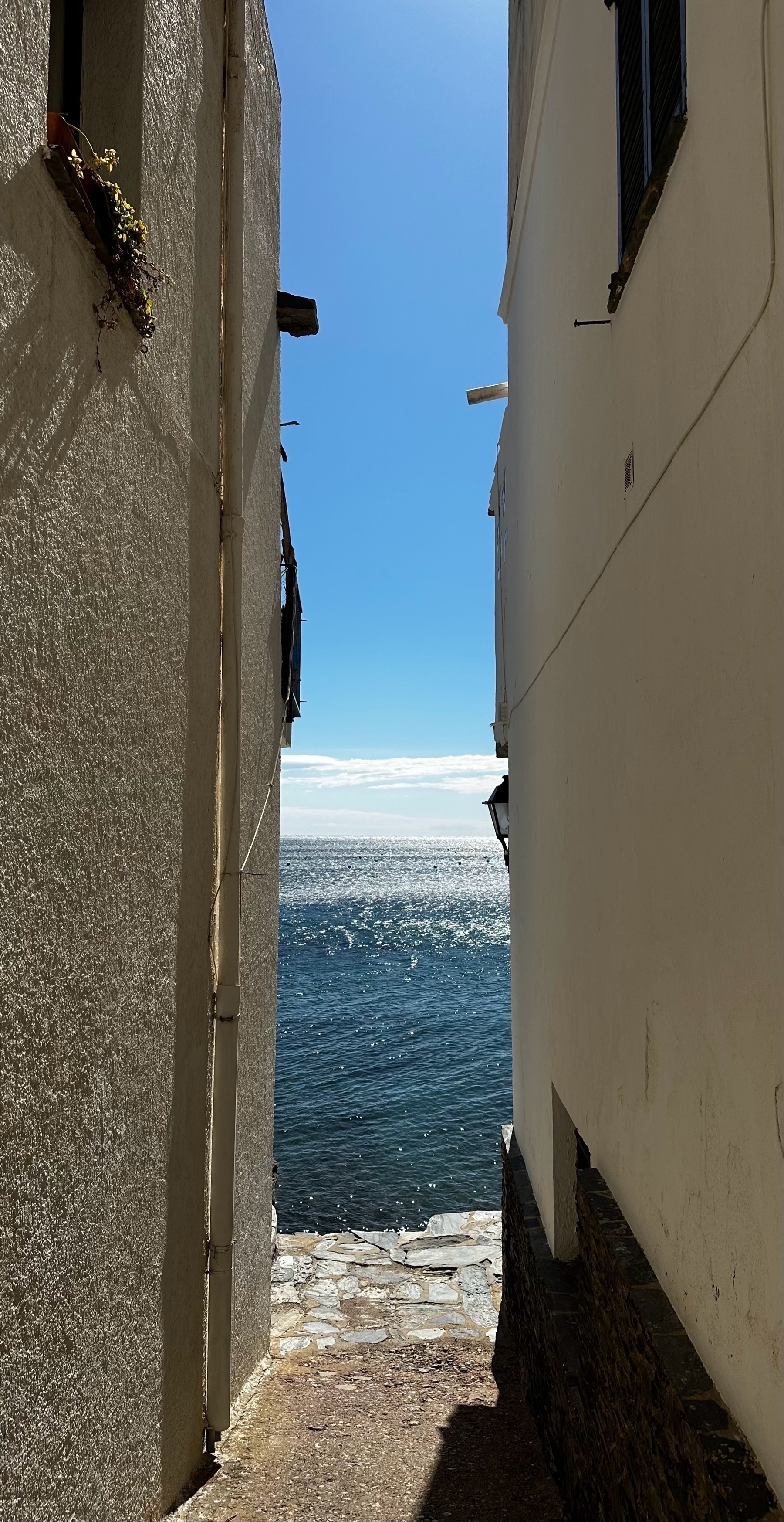 A narrow alley between white buildings leads directly to the sea under a bright sky.
Spanish: Un estrecho callejón entre edificios blancos conduce directamente al mar bajo un cielo luminoso.
Basque: Kale estu bat eraikin zuri artean zehar zuzenean itsasoraino doa zeru argi baten azpian.