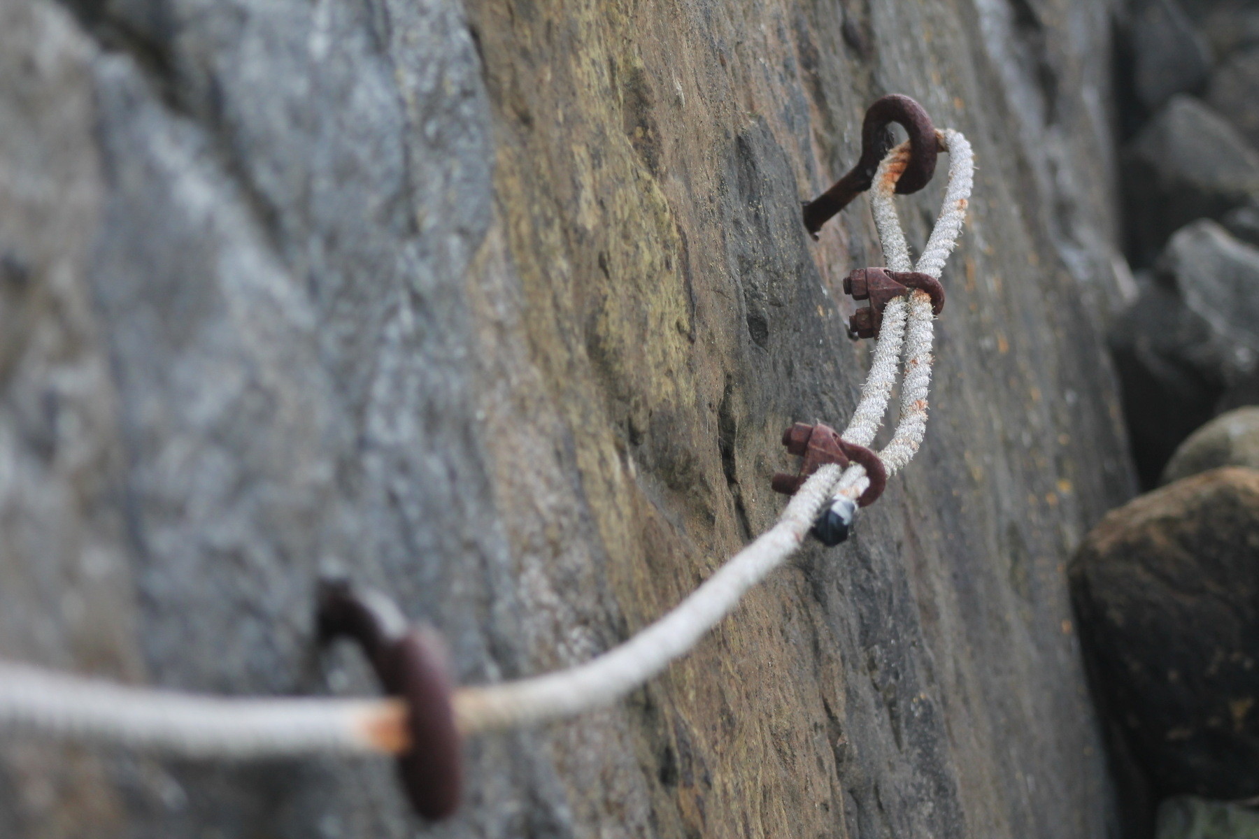 An old rope tied to a wall with rusty iron rings